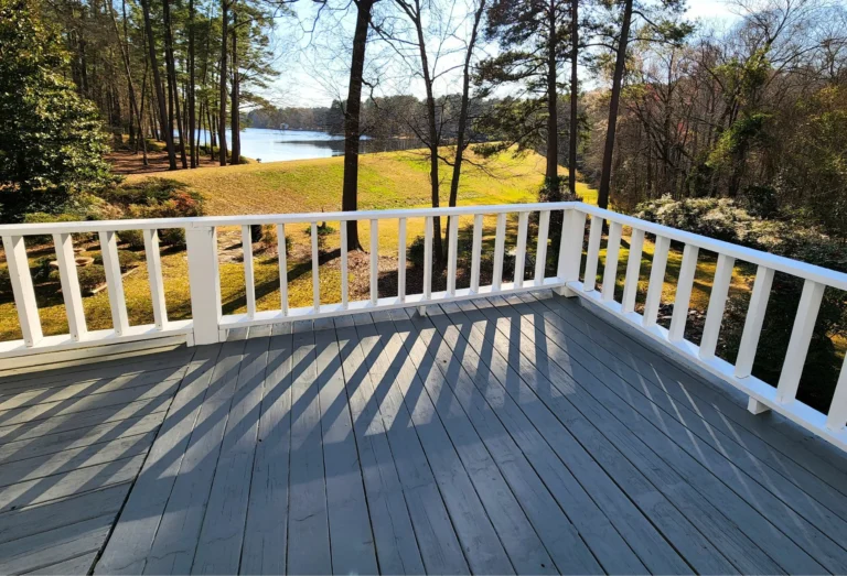 Finished gray deck boards beside white railings and outdoor furniture